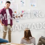 Grupo em reunião com apresentação de dados e gráficos, representando o conceito de marketing humanizado.