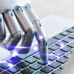 Mão robótica, digitando em um notebook, simbolizando o uso da IA na produção de conteúdo.