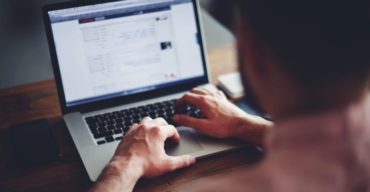 Saiba mais sobre funil de vendas e mídia paga com a Trii! Profissional analisa métricas em notebook para otimizar o funil de vendas e mídia paga