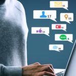 Pessoa digita no notebook cercada por ícones digitais em SEO para médias empresas.