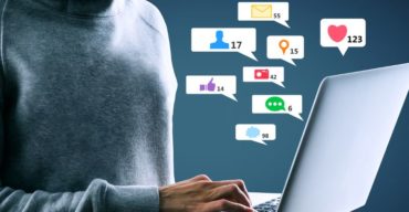 Saiba mais sobre SEO para médias empresas com a Trii! Pessoa digita no notebook cercada por ícones digitais em SEO para médias empresas.