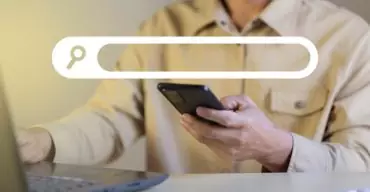 Descubra Como fazer minha empresa aparecer no Google homem mexendo no celular e procurando Como fazer minha empresa aparecer no Google