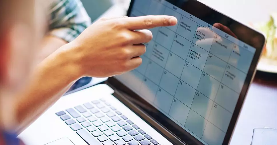 Pessoa organiza datas e publicações em um calendário de conteúdo no notebook.